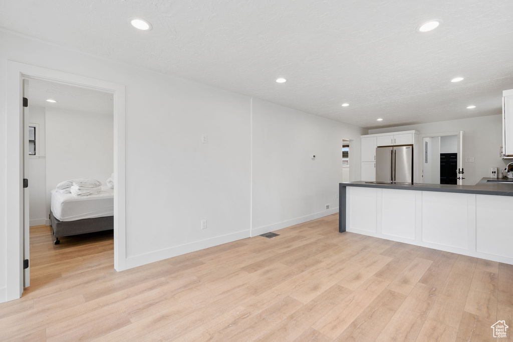 Kitchen featuring white cabinets, sink, high end fridge, and light hardwood / wood-style flooring