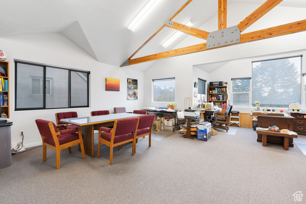 Carpeted dining area with a healthy amount of sunlight, beam ceiling, and high vaulted ceiling