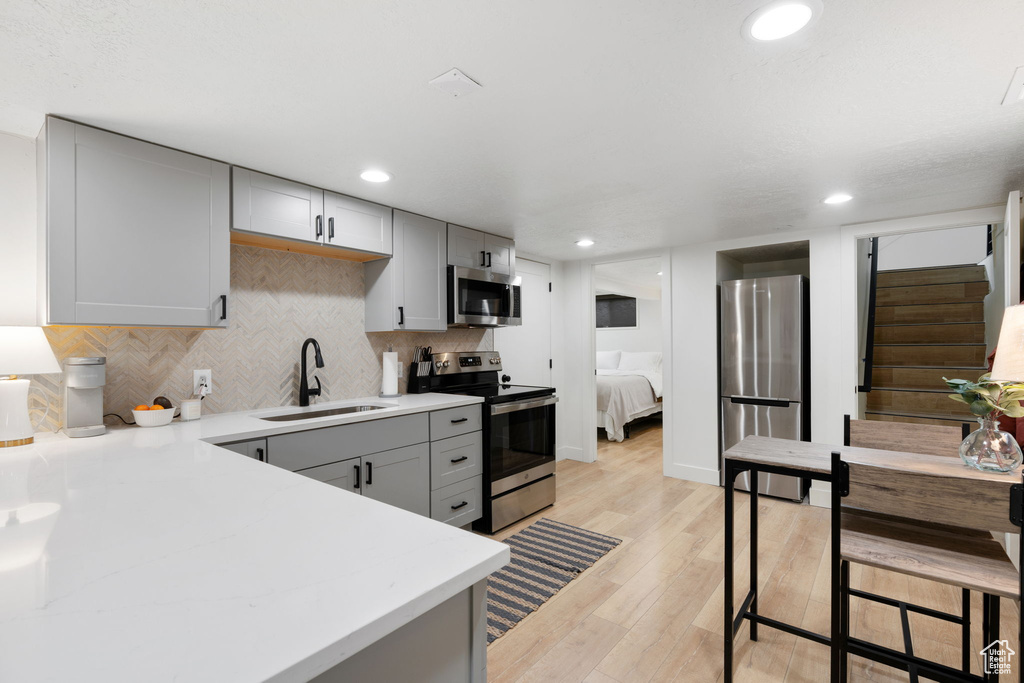 Kitchen featuring gray cabinets, light hardwood / wood-style flooring, stainless steel appliances, and sink
