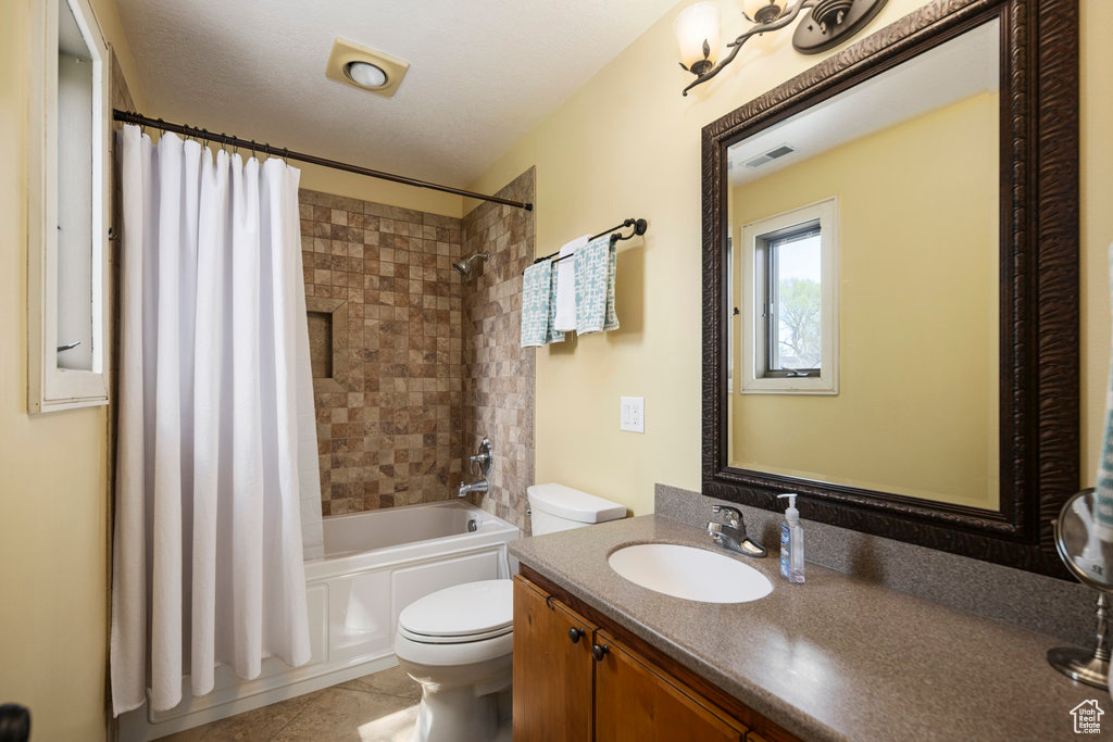 Full bathroom featuring vanity, shower / bathtub combination with curtain, toilet, and tile flooring