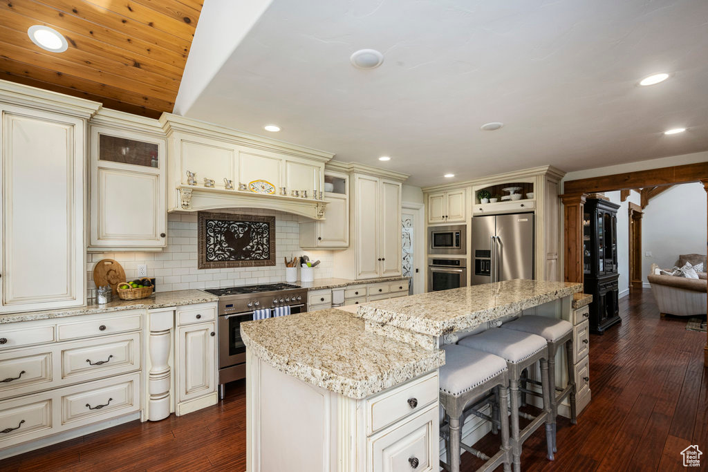 Kitchen featuring a center island, backsplash, premium appliances, and dark wood-type flooring
