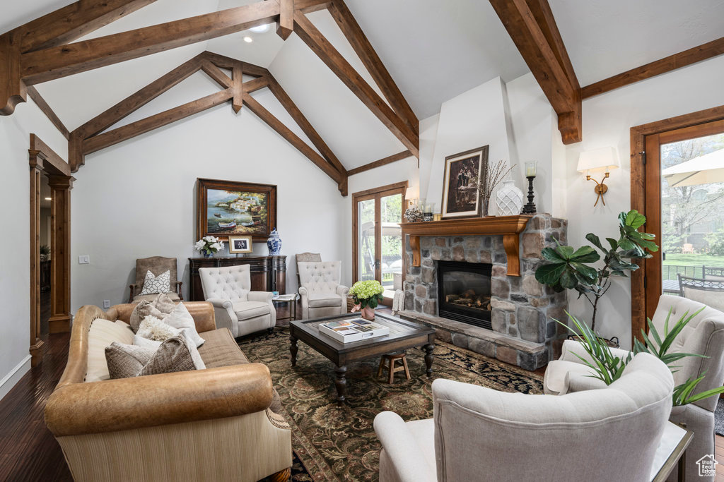 Living room featuring beamed ceiling, high vaulted ceiling, hardwood / wood-style flooring, and a stone fireplace