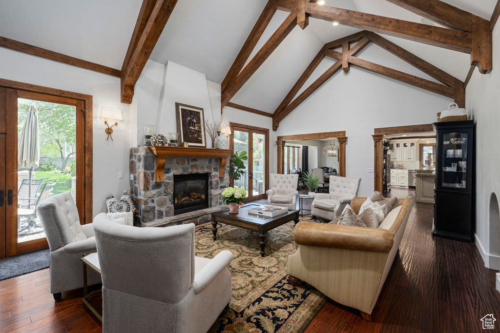 Living room featuring a stone fireplace, high vaulted ceiling, beam ceiling, and dark hardwood / wood-style floors