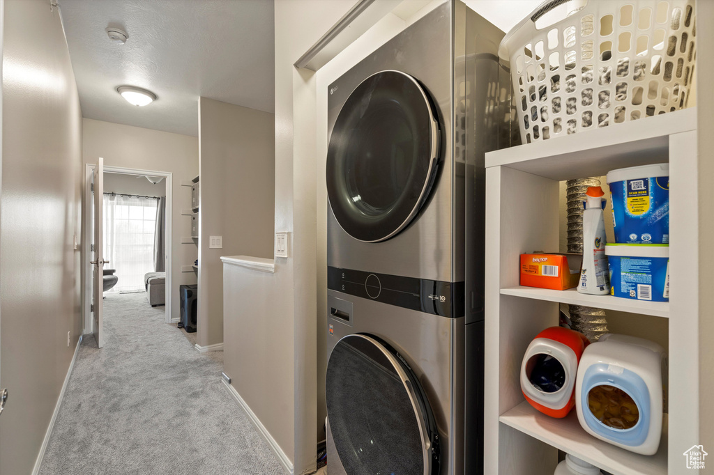 Laundry room featuring light colored carpet and stacked washer / drying machine