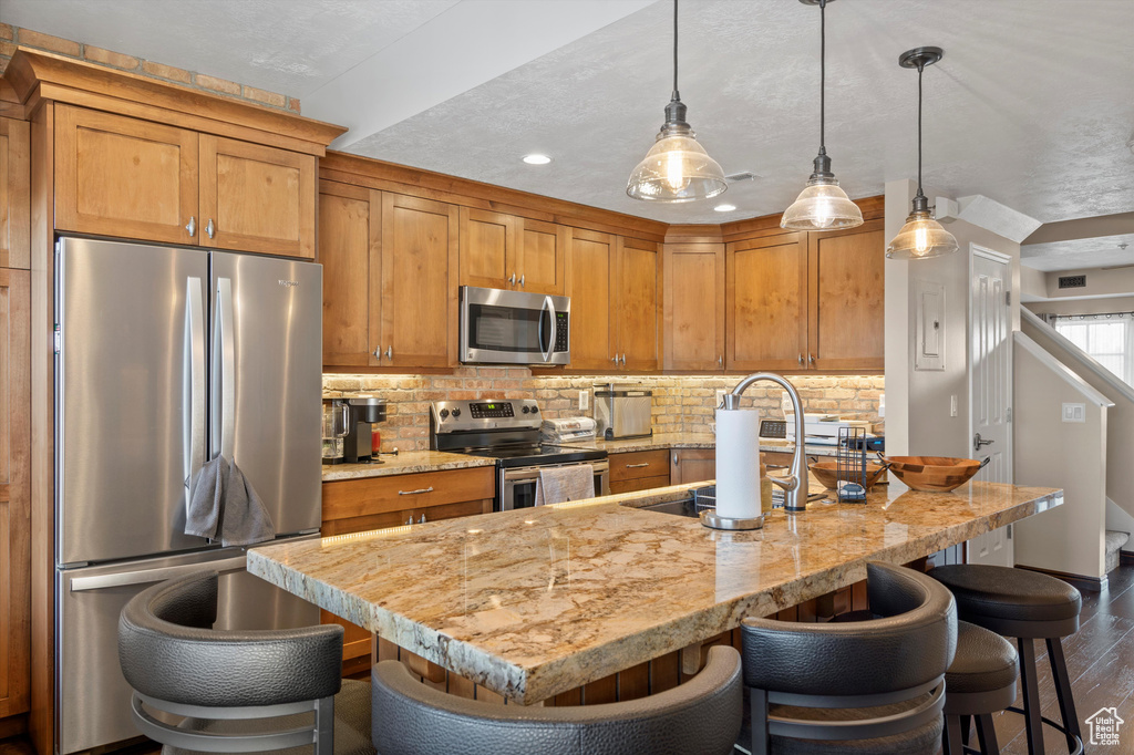 Kitchen with tasteful backsplash, pendant lighting, stainless steel appliances, and dark hardwood / wood-style floors