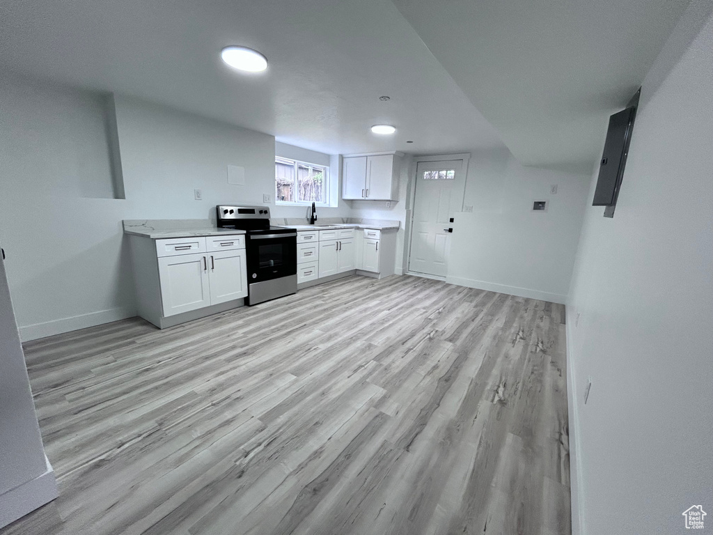 Kitchen with white cabinets, sink, light hardwood / wood-style flooring, and stainless steel electric range