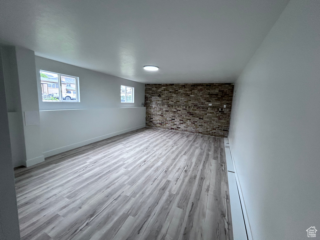 Unfurnished room featuring light hardwood / wood-style floors and brick wall