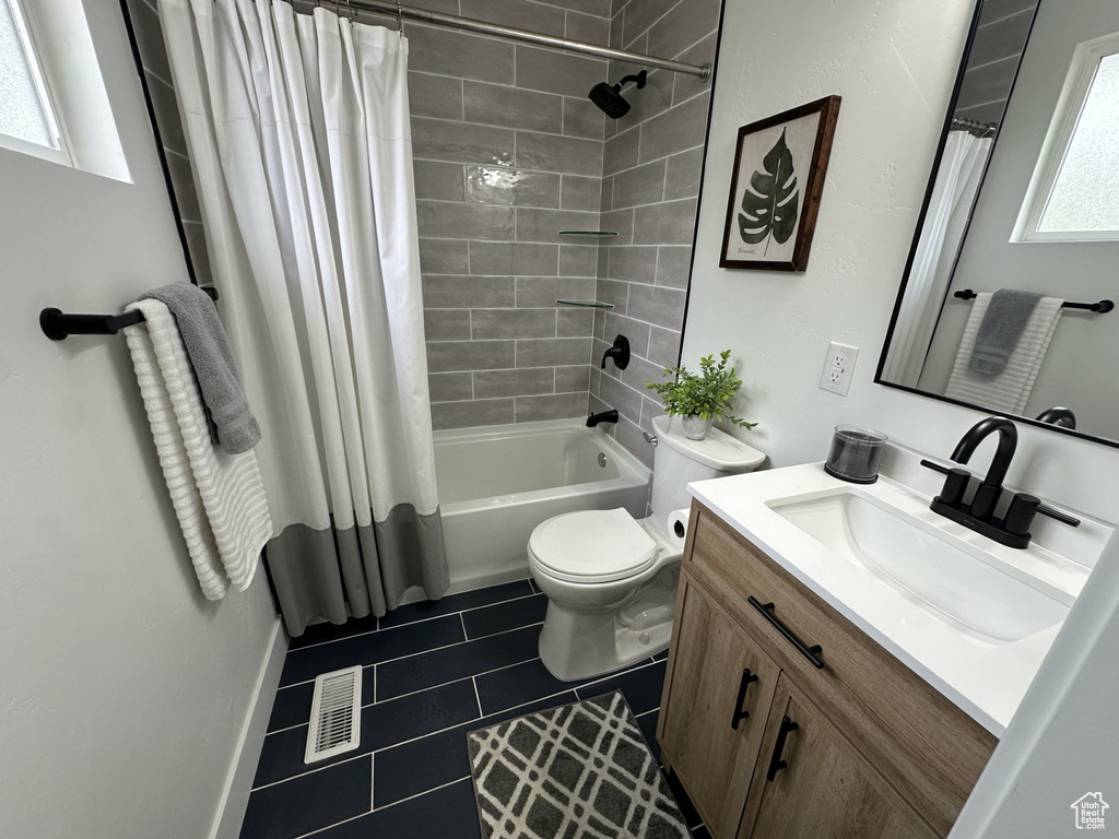 Full bathroom with a wealth of natural light, shower / bathtub combination with curtain, toilet, and vanity
