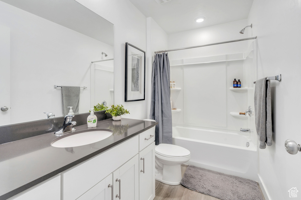 Full bathroom featuring hardwood / wood-style flooring, shower / tub combo, toilet, and large vanity