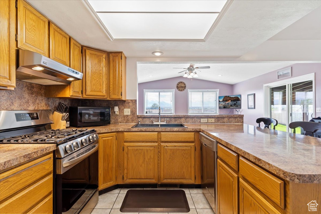 Kitchen featuring backsplash, appliances with stainless steel finishes, sink, ceiling fan, and lofted ceiling