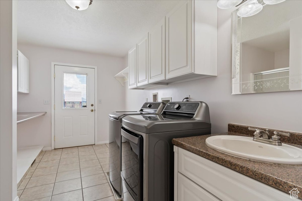 Washroom with light tile floors, cabinets, washer and clothes dryer, sink, and washer hookup