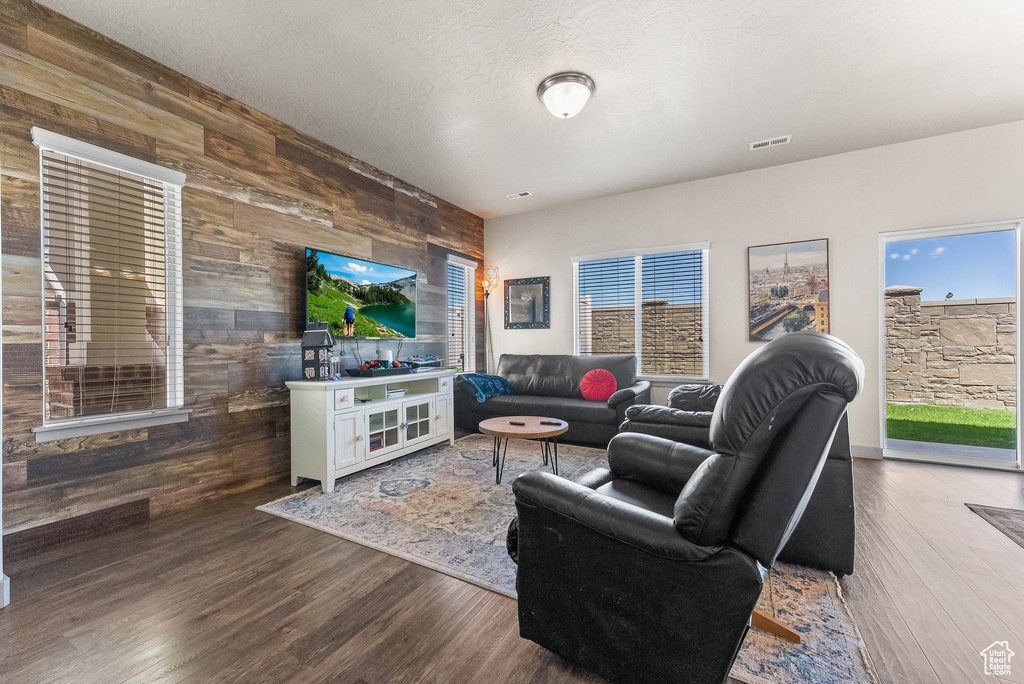 Living room with a textured ceiling, hardwood / wood-style flooring, and wooden walls