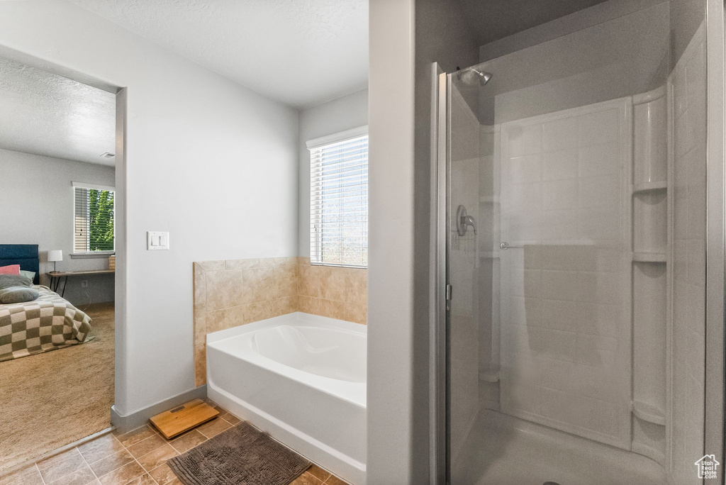 Bathroom with a wealth of natural light, tile floors, separate shower and tub, and a textured ceiling