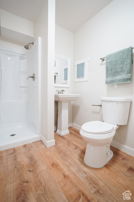 Bathroom with a shower, hardwood / wood-style flooring, and toilet