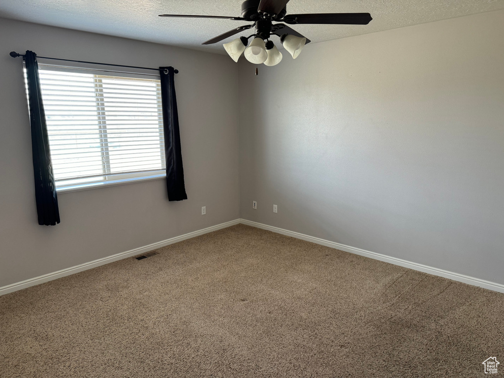 Carpeted empty room with ceiling fan and a textured ceiling