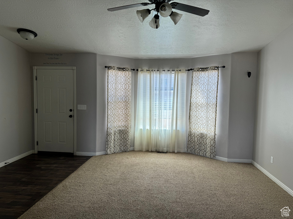 Empty room featuring hardwood / wood-style floors, ceiling fan, and a textured ceiling
