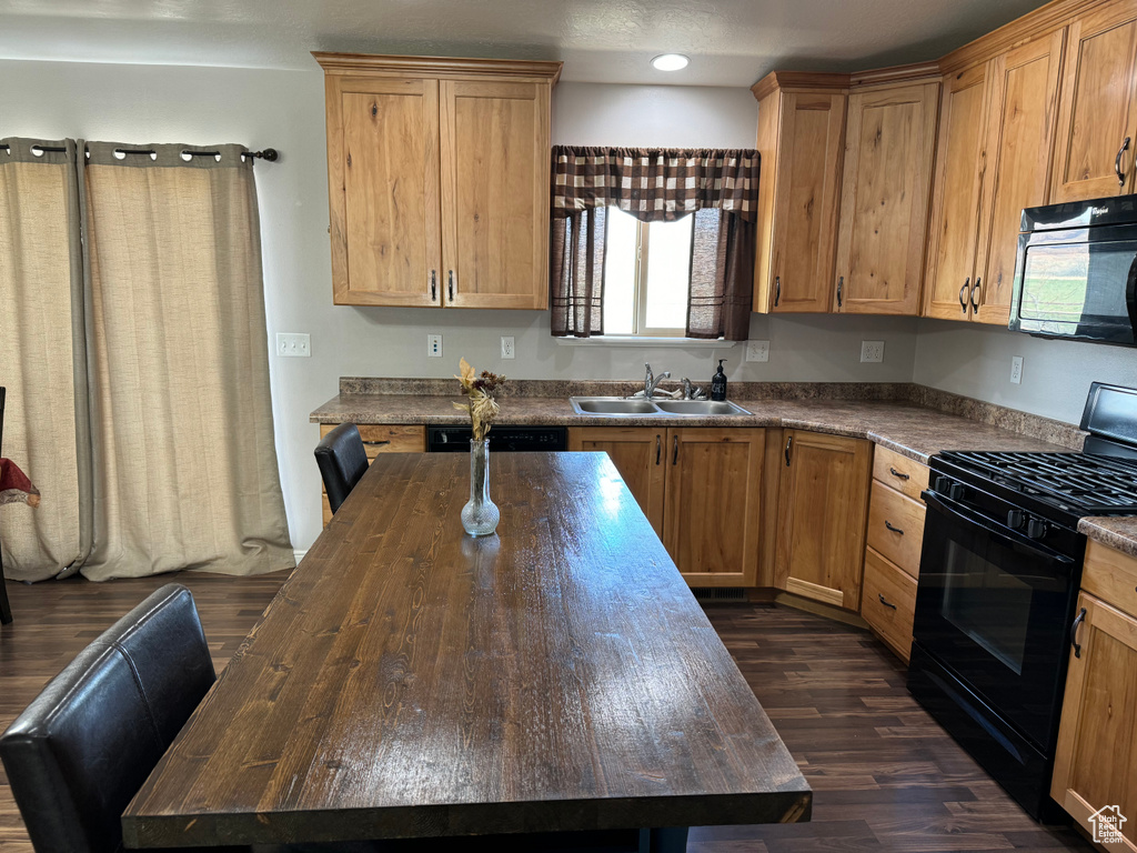Kitchen with dark hardwood / wood-style floors, butcher block countertops, sink, and black appliances