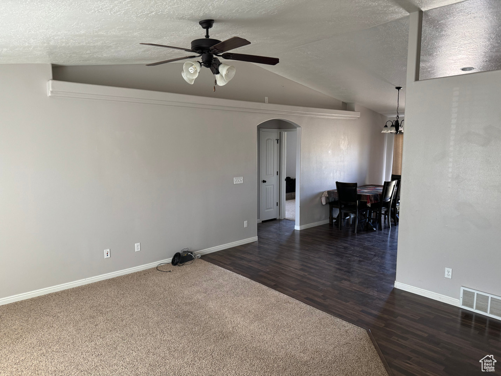 Spare room with lofted ceiling, dark colored carpet, ceiling fan, and a textured ceiling