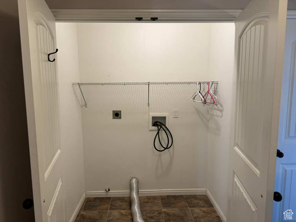 Washroom featuring electric dryer hookup, hookup for a washing machine, and dark tile flooring