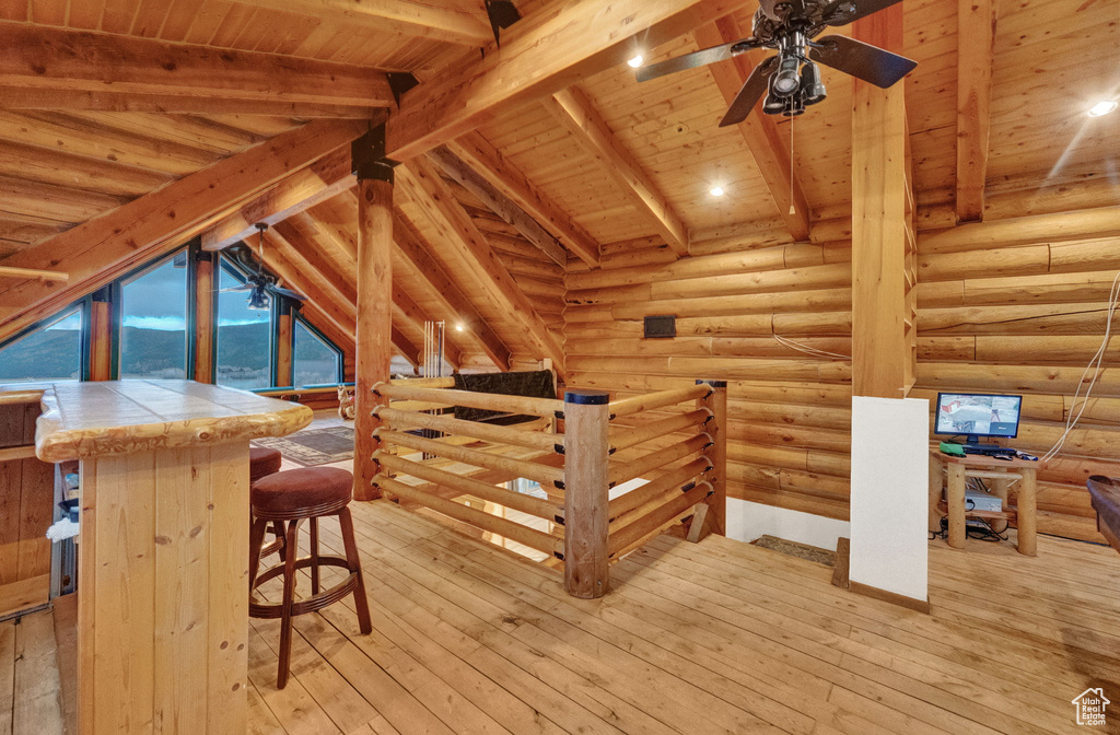 Interior space featuring wood ceiling, light hardwood / wood-style flooring, vaulted ceiling with beams, and rustic walls