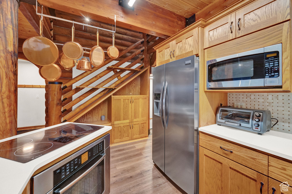 Kitchen featuring light hardwood / wood-style floors, stainless steel appliances, and wood ceiling