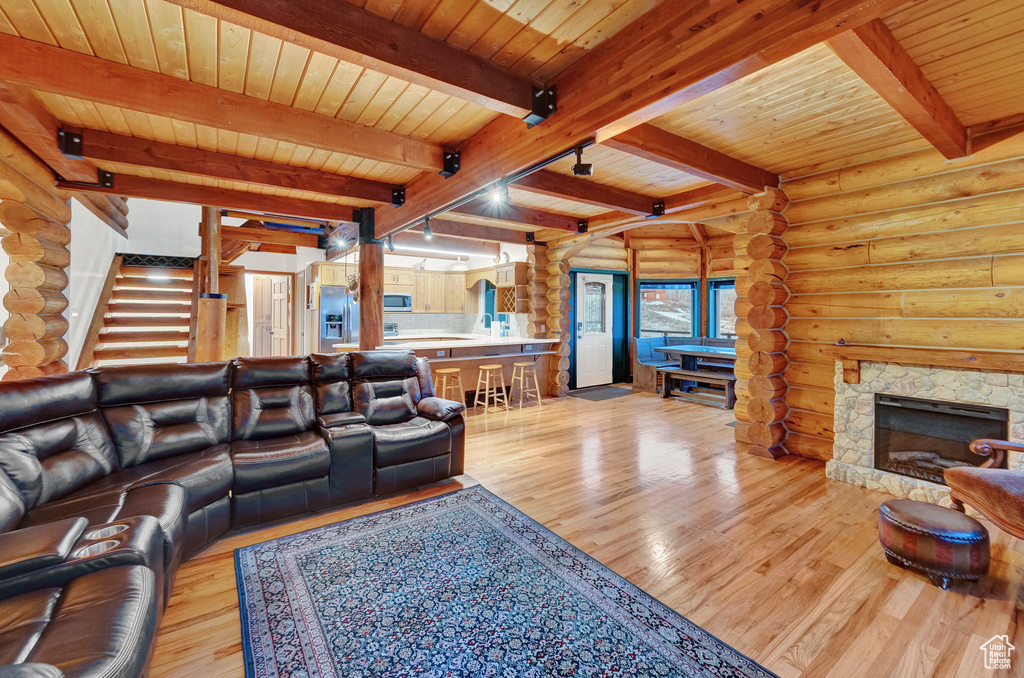 Living room featuring log walls, light hardwood / wood-style flooring, a fireplace, and beam ceiling