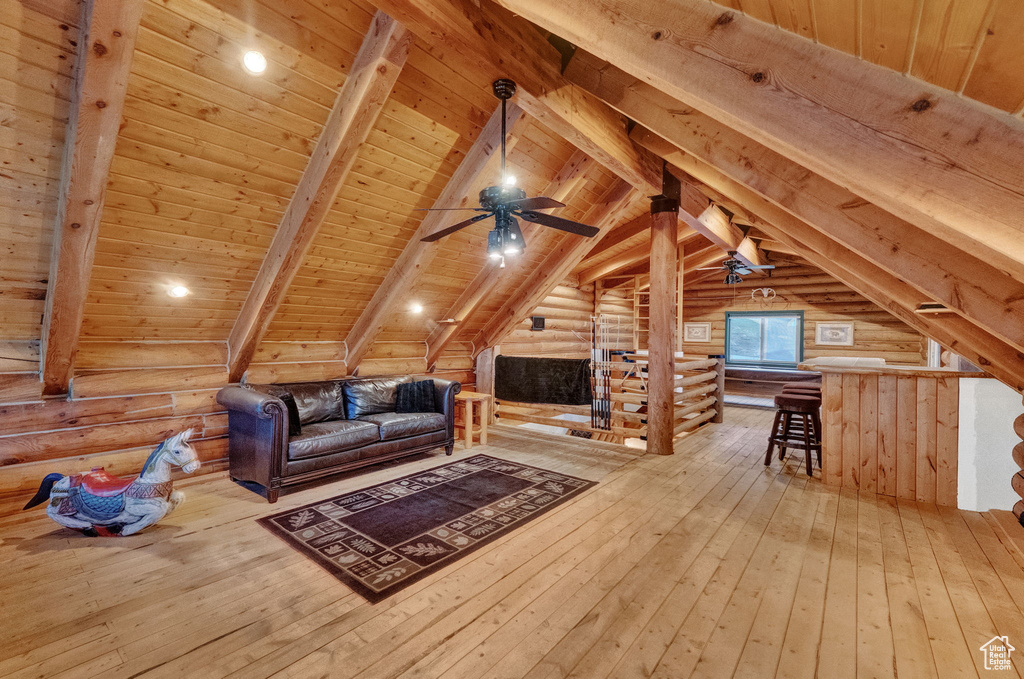 Bonus room featuring wood ceiling, light hardwood / wood-style flooring, lofted ceiling with beams, and rustic walls
