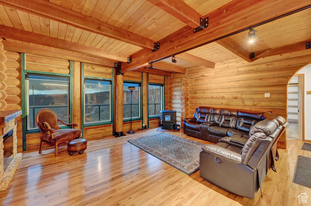 Living room with rustic walls, beamed ceiling, wooden ceiling, and light wood-type flooring