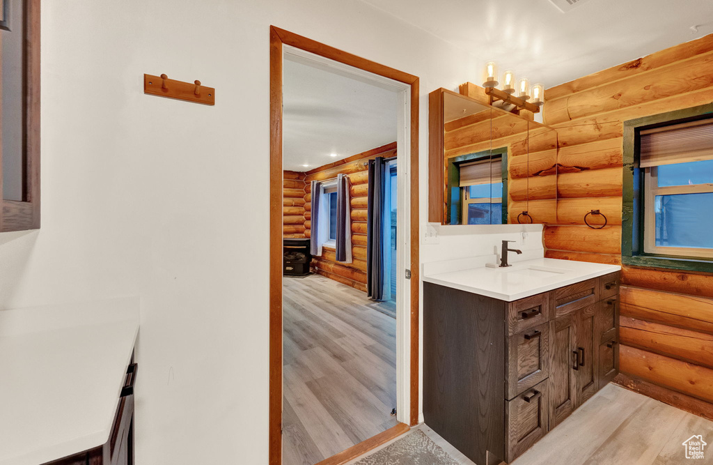 Bathroom featuring wood-type flooring, vanity with extensive cabinet space, and rustic walls
