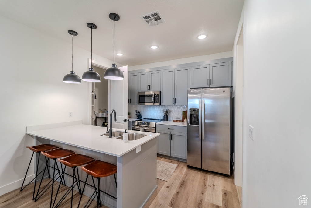 Kitchen featuring kitchen peninsula, appliances with stainless steel finishes, sink, and light wood-type flooring