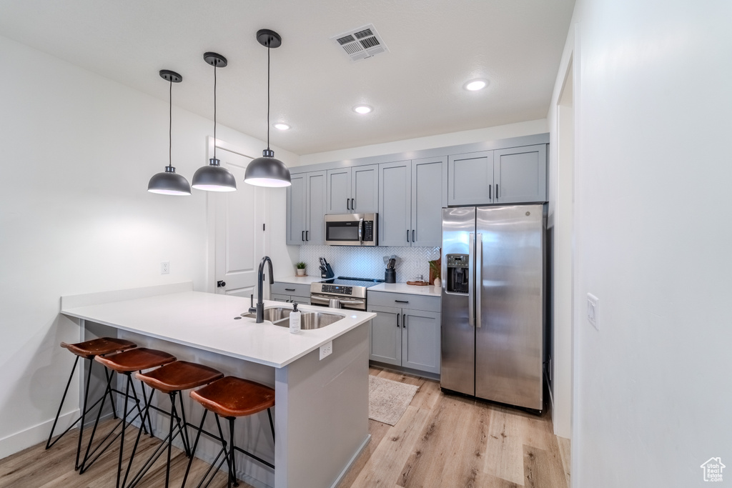 Kitchen featuring sink, stainless steel appliances, kitchen peninsula, and light wood-type flooring
