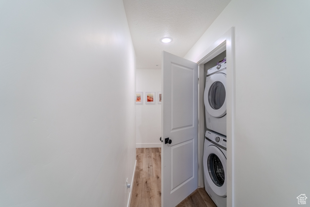 Laundry room featuring wood-type flooring and stacked washer / drying machine