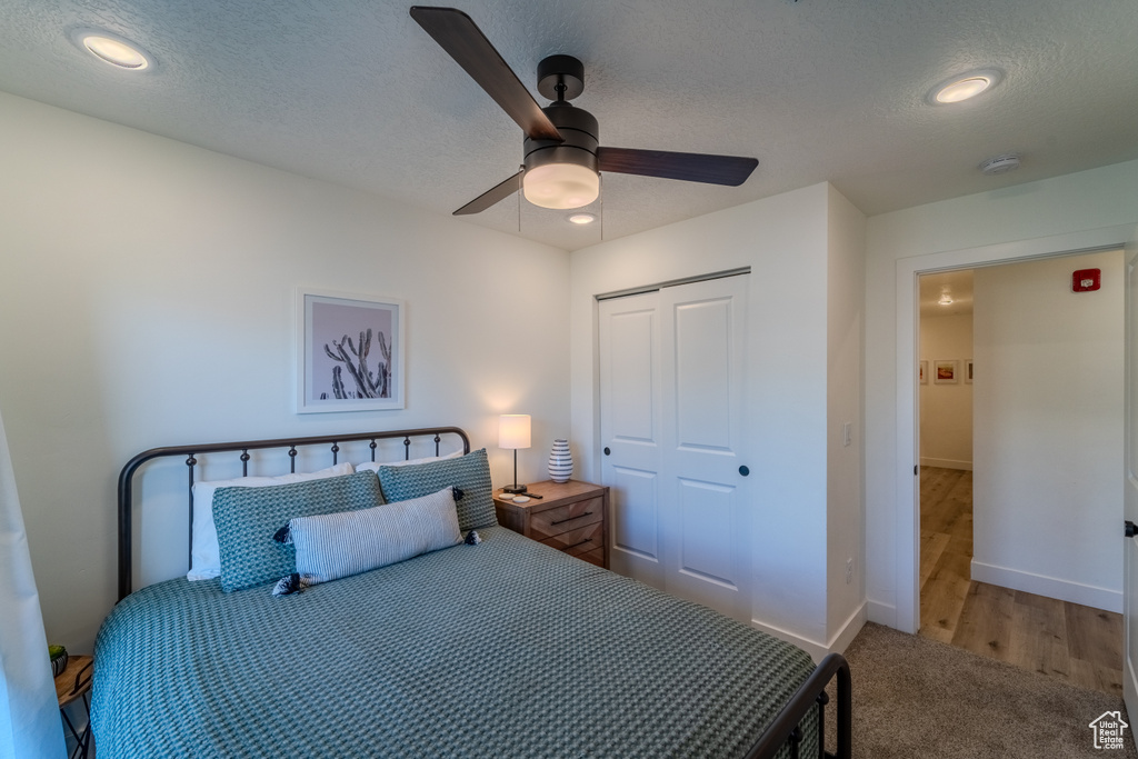 Bedroom with a closet, a textured ceiling, hardwood / wood-style floors, and ceiling fan