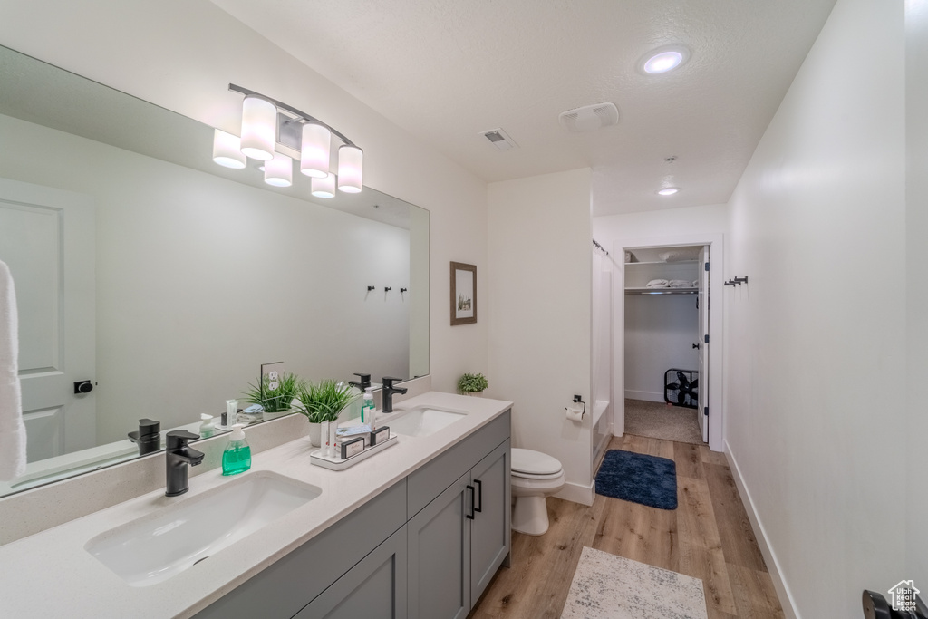 Bathroom with hardwood / wood-style floors, dual bowl vanity, and toilet