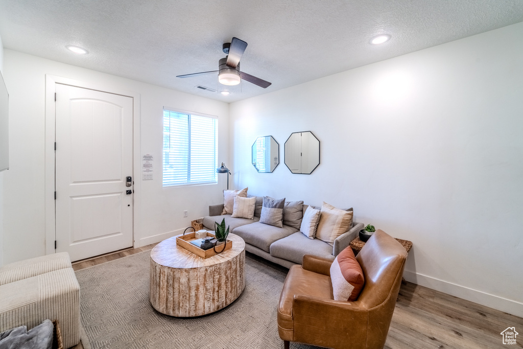 Living room with wood-type flooring, ceiling fan, and a textured ceiling