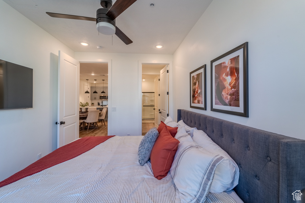 Bedroom with hardwood / wood-style flooring, connected bathroom, ceiling fan, and fridge