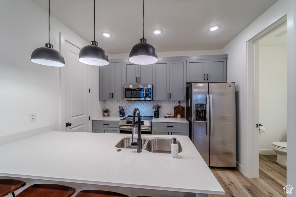 Kitchen featuring decorative light fixtures, light hardwood / wood-style flooring, tasteful backsplash, and stainless steel appliances