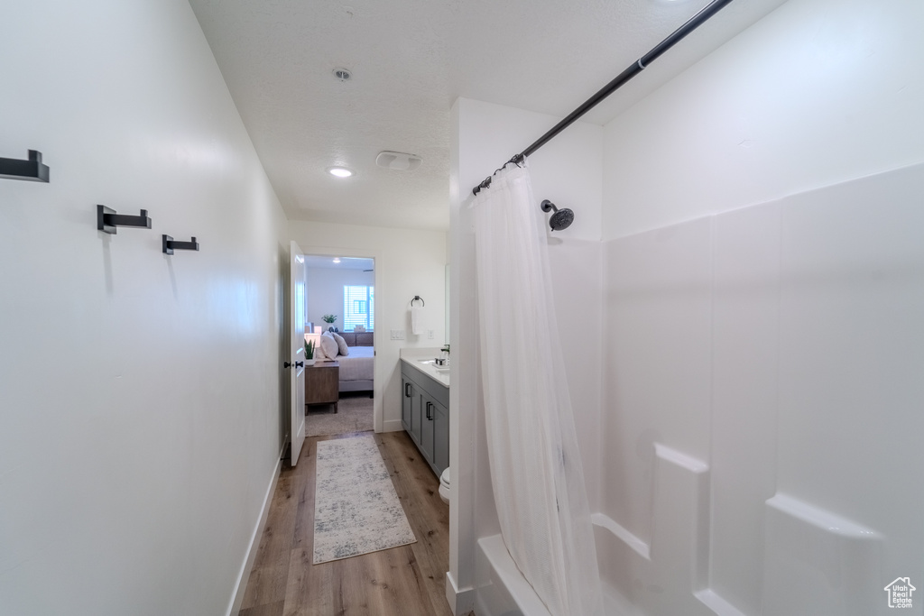 Full bathroom with hardwood / wood-style floors, vanity, toilet, and shower / bath combo with shower curtain