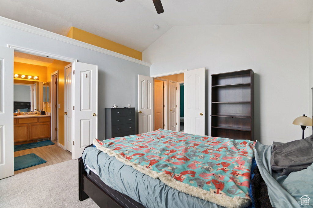 Bedroom with ensuite bath, hardwood / wood-style floors, ceiling fan, and high vaulted ceiling