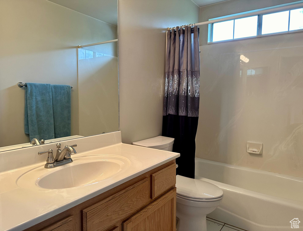 Full bathroom featuring tile floors, vanity with extensive cabinet space, toilet, and shower / tub combo with curtain