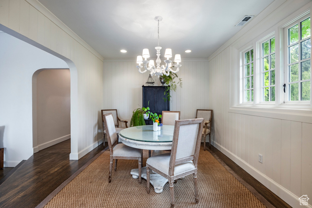 Dining area featuring dark hardwood / wood-style flooring, crown molding, a wealth of natural light, and an inviting chandelier