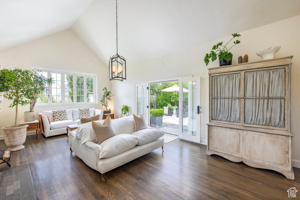 Living room featuring high vaulted ceiling, dark wood-type flooring, and a chandelier
