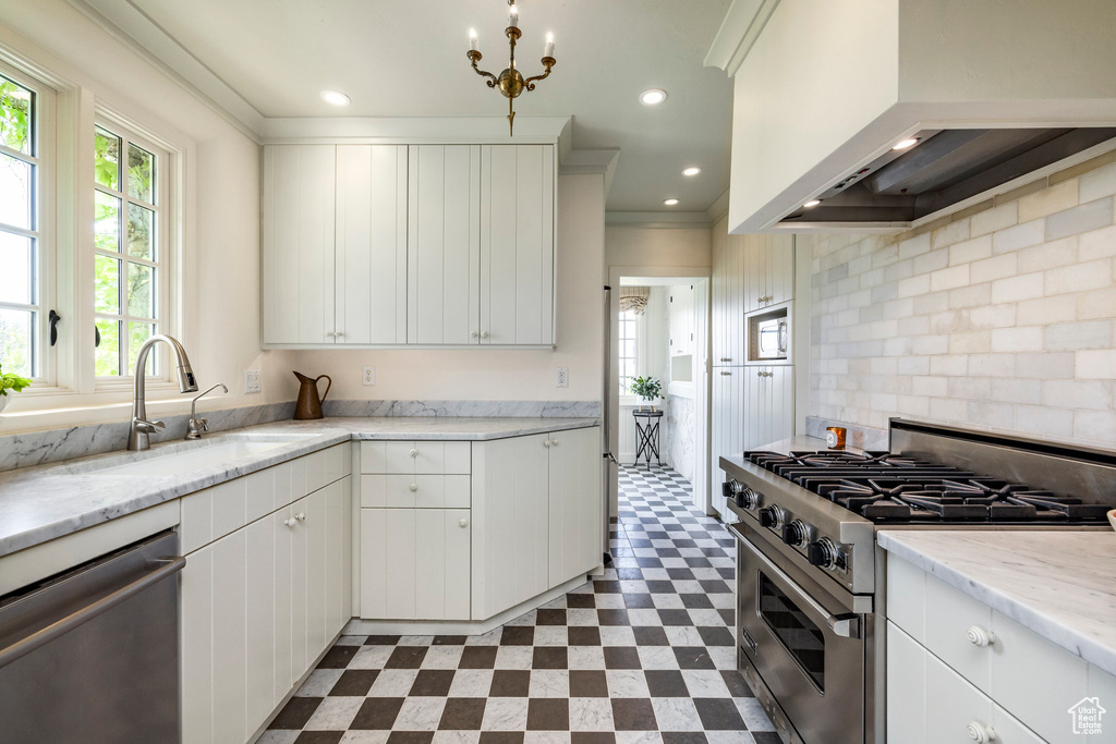 Kitchen featuring appliances with stainless steel finishes, custom exhaust hood, white cabinets, and light tile flooring