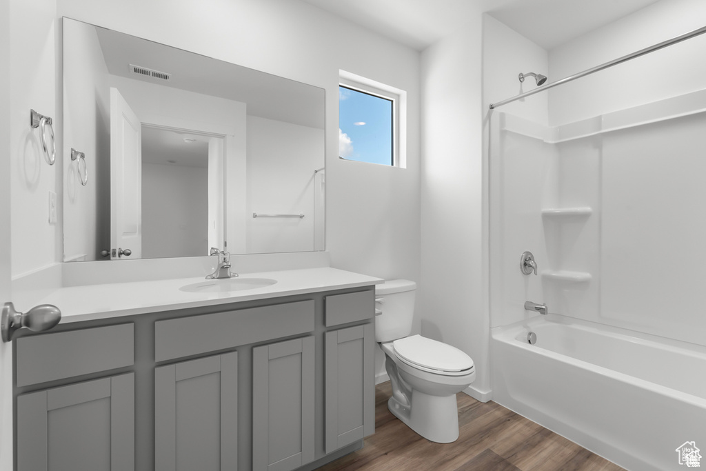 Full bathroom with hardwood / wood-style floors, vanity, toilet, and shower / tub combination