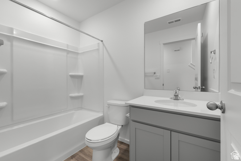 Full bathroom featuring wood-type flooring, vanity, bathtub / shower combination, and toilet