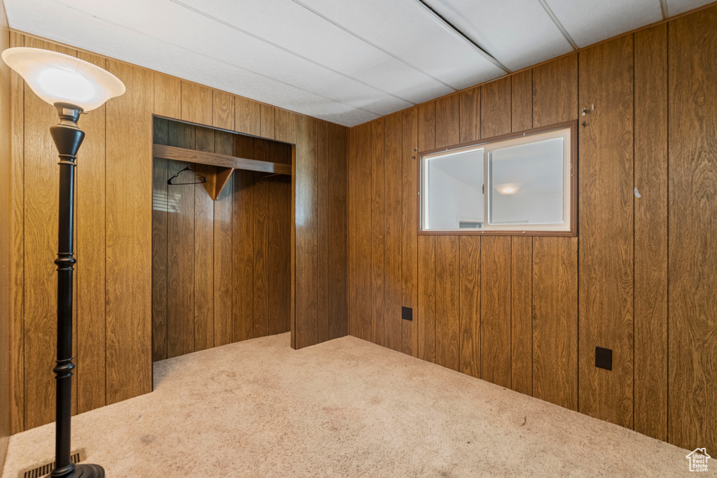 Unfurnished bedroom featuring wood walls, a closet, and carpet floors