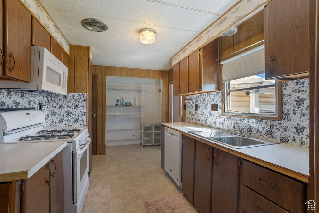 Kitchen with sink, white appliances, tasteful backsplash, and light tile floors