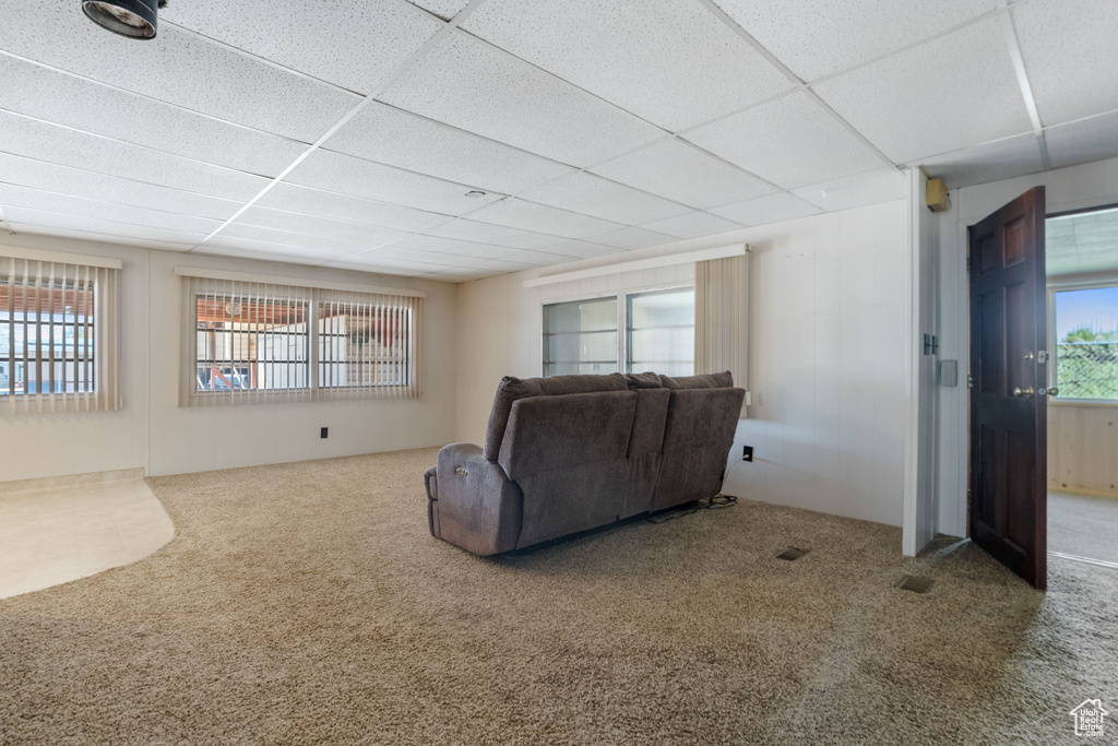 Living room featuring a drop ceiling and carpet flooring