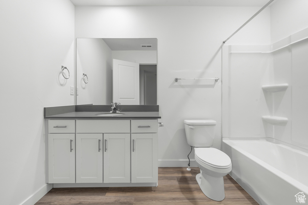 Full bathroom featuring hardwood / wood-style flooring, toilet, shower / bathing tub combination, and vanity