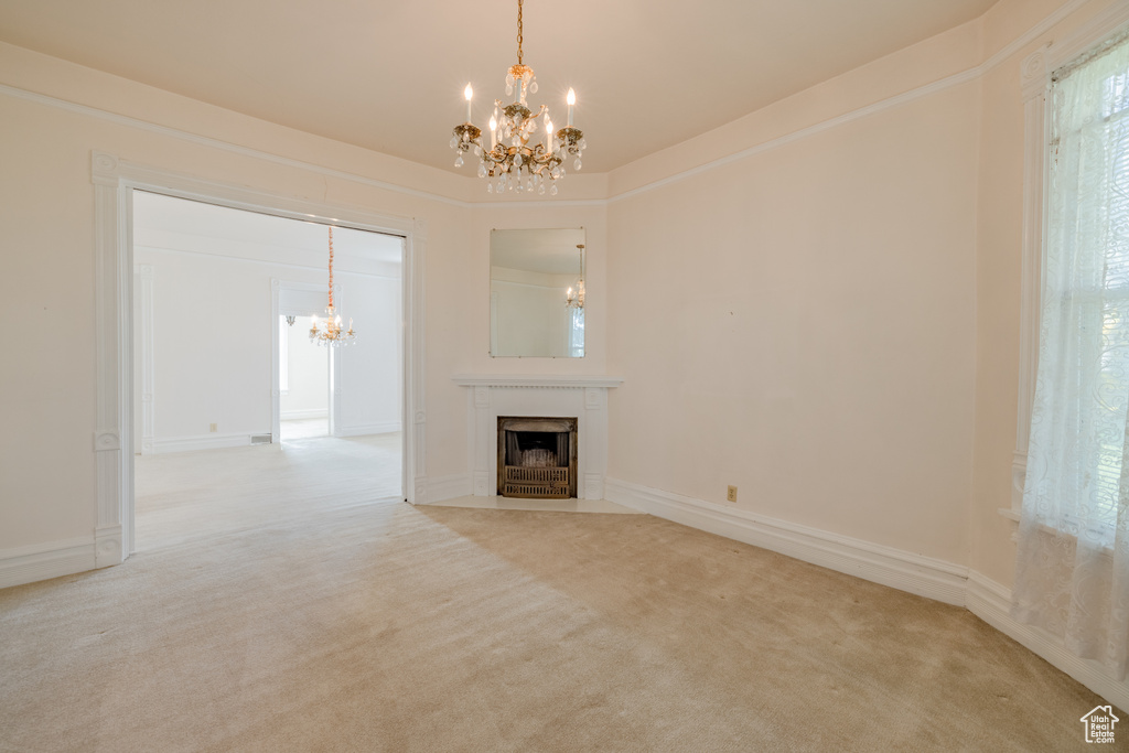 Unfurnished living room with carpet floors and an inviting chandelier